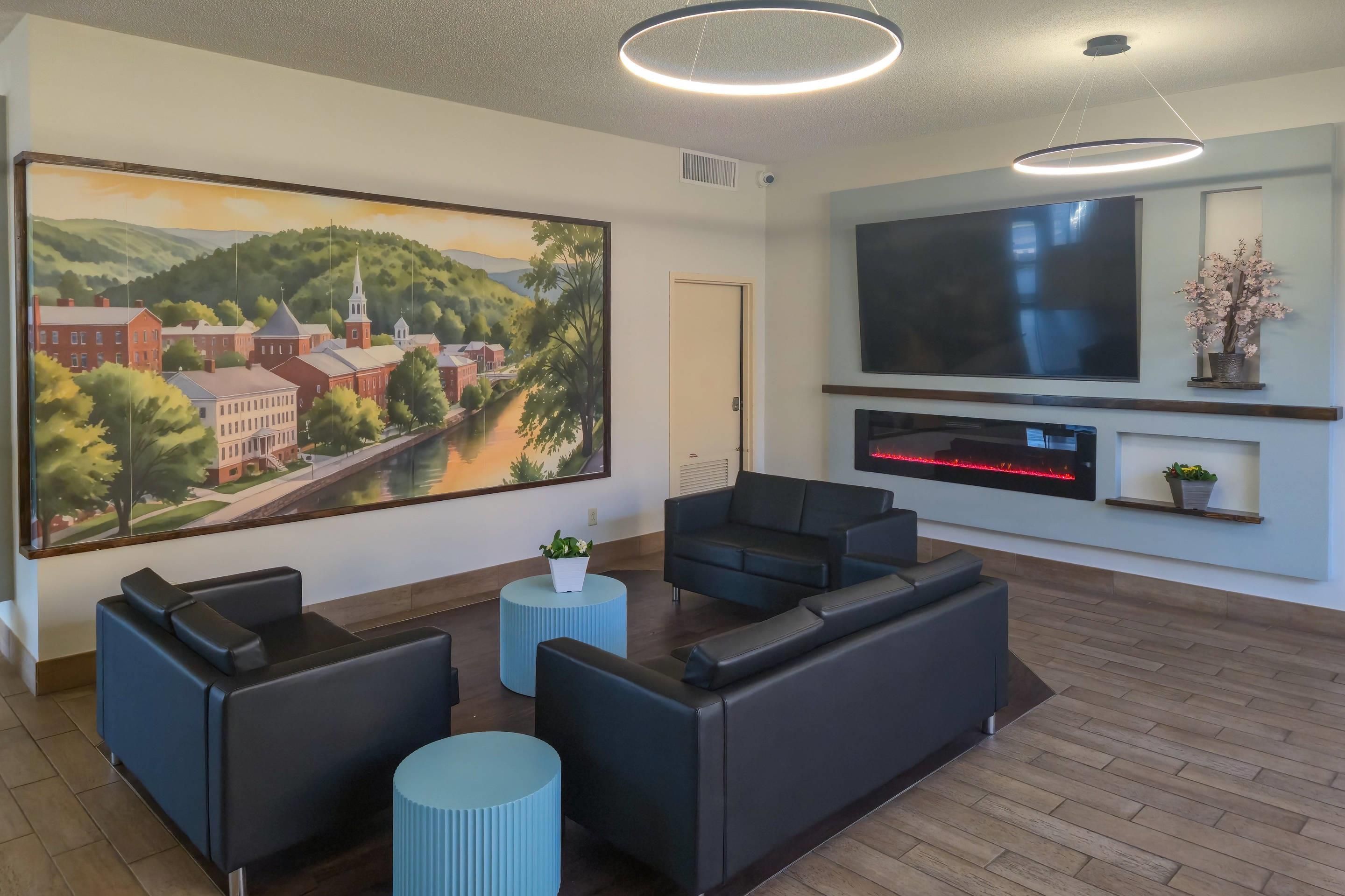 A modern living room with a large painting, a flat-screen TV, and comfortable seating.