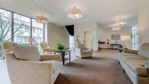 A spacious living room with a large window, a staircase, and multiple seating areas.