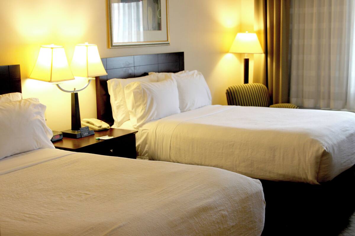 Une chambre d’hôtel avec deux lits, des lampes de chevet, une table de chevet avec un téléphone et une tête de lit.