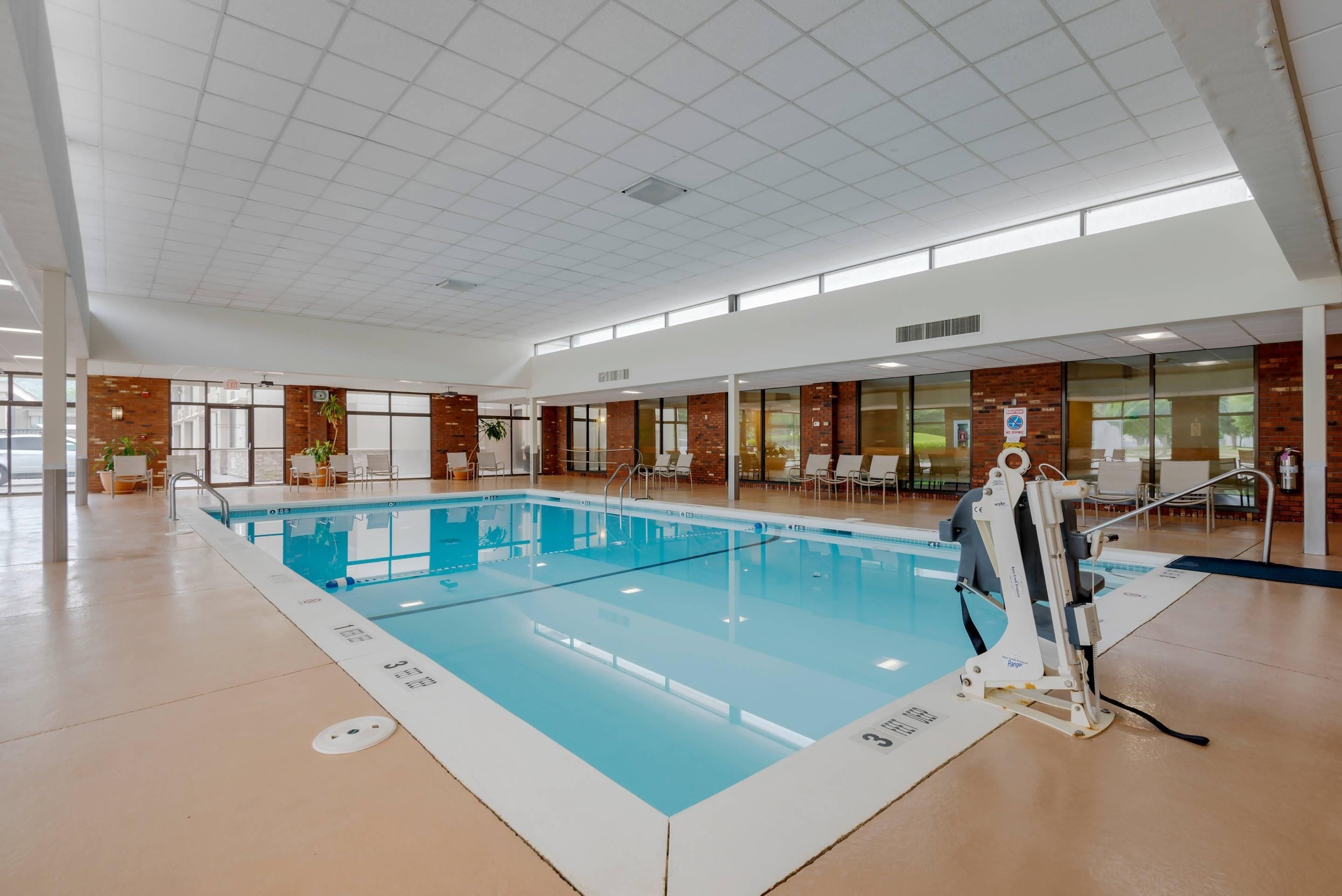 Une piscine intérieure à l’eau claire, dotée d’un plongeoir et entourée de chaises longues.