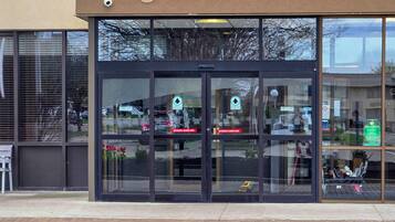 A building with a glass entrance, automatic sliding doors, and a security camera.
