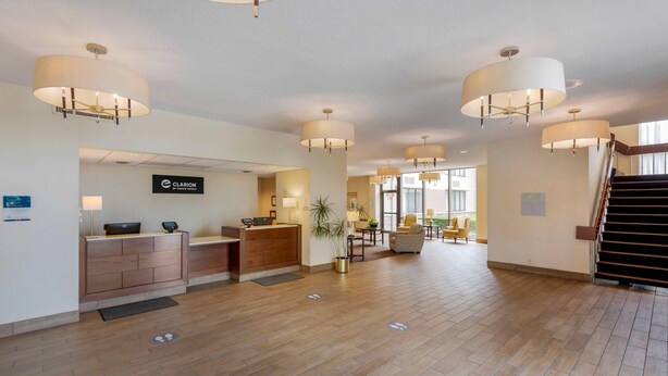 A hotel lobby with a reception desk, multiple seating areas, and a staircase.
