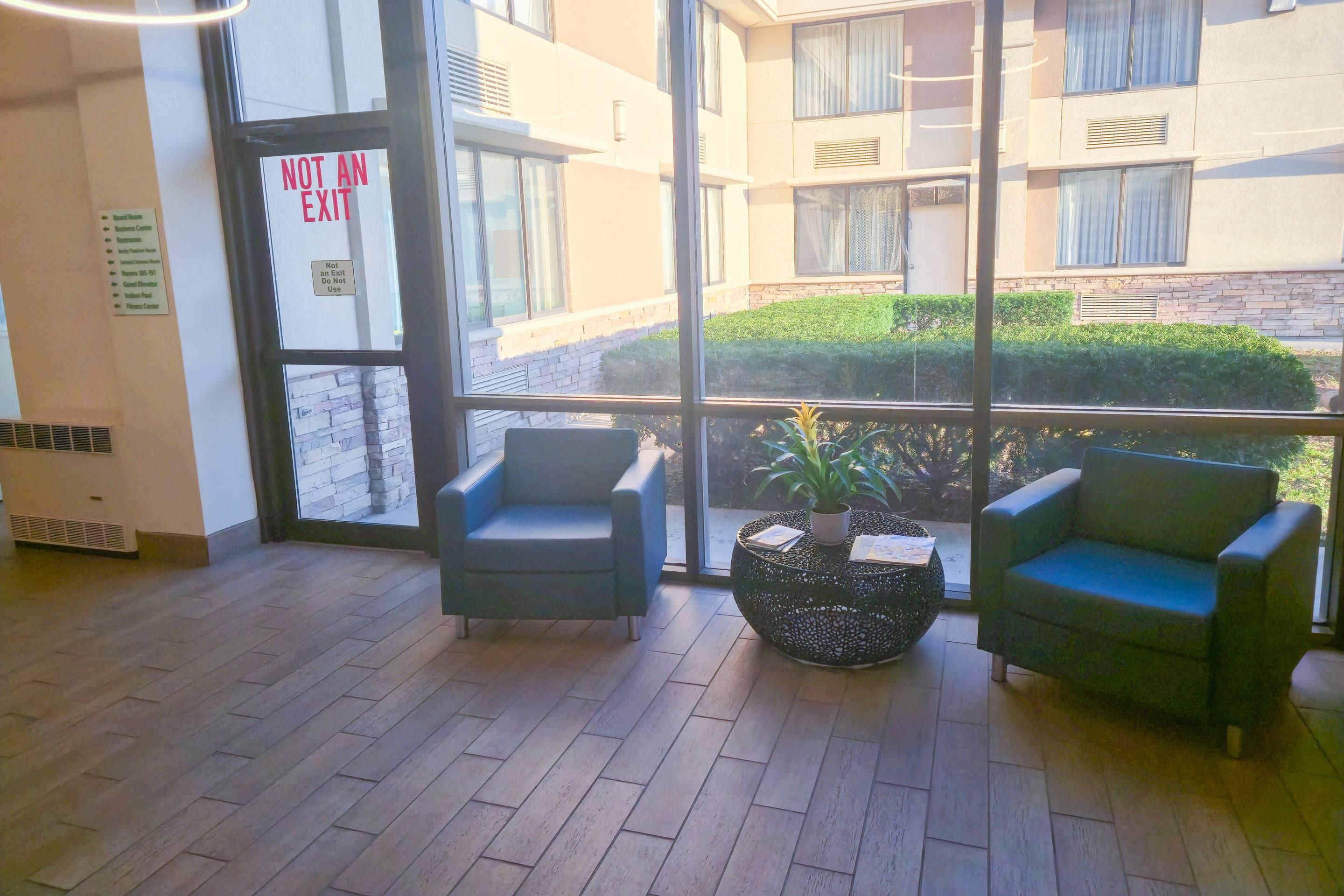 A hotel lobby with a glass door marked 'NOT AN EXIT' and a sign indicating 'Business Center' and 'Fitness Center' on the left.