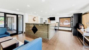 A modern hotel lobby with a reception desk, seating area, and large windows. - Comfort Inn near Great Smoky Mountain National Park (Maggie Valley)
