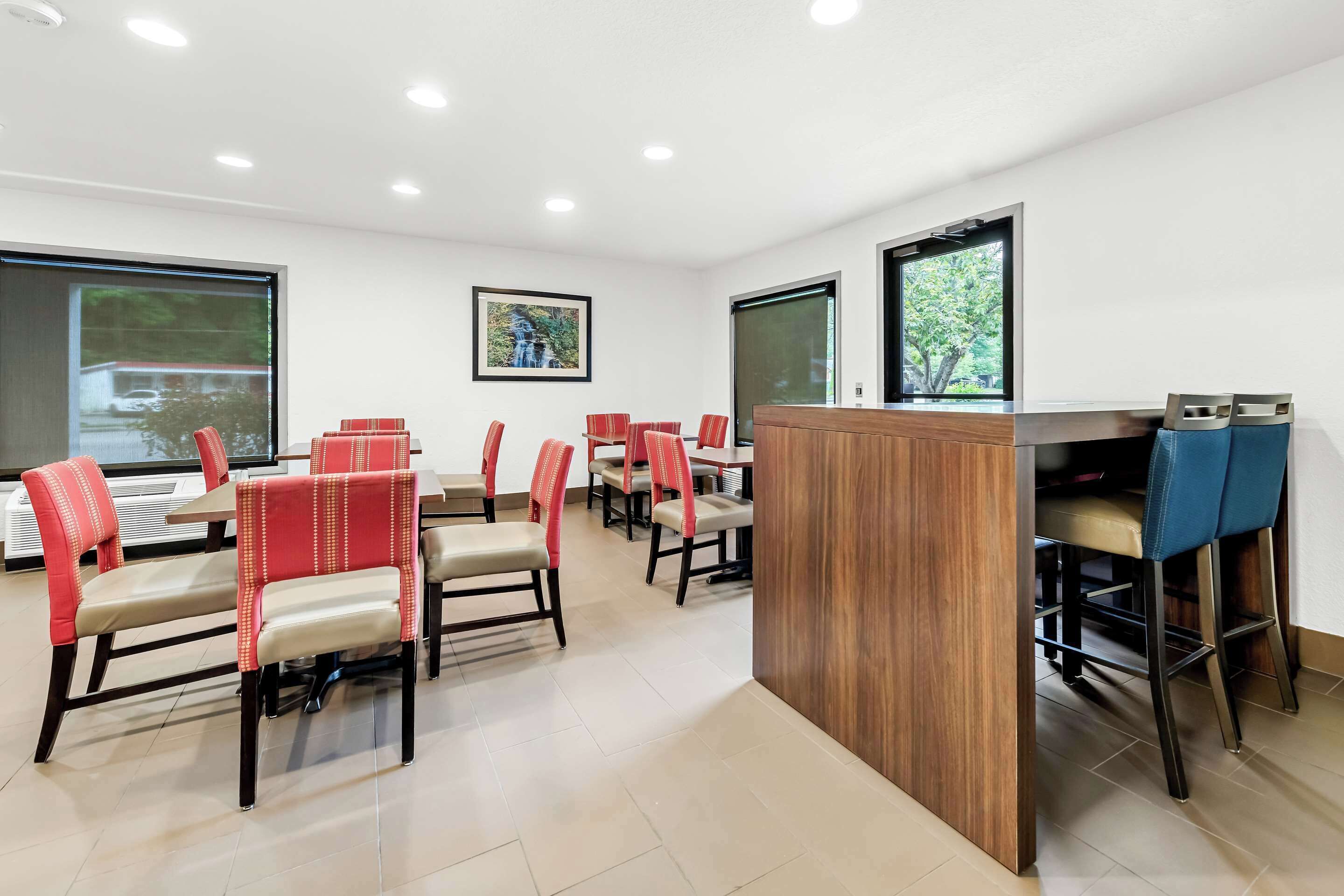 A conference room with multiple tables and chairs, large windows, and a wooden podium.