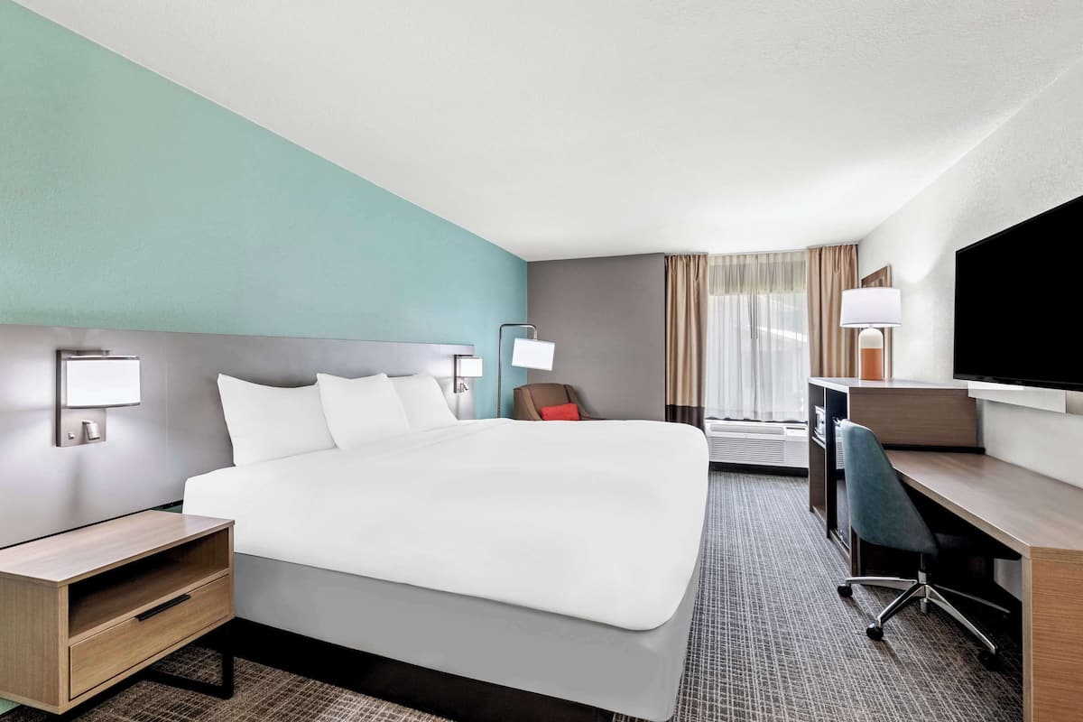A hotel room with a bed, desk, and TV.