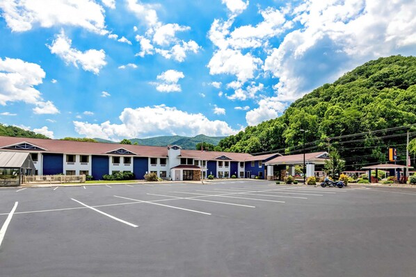 A motel with a parking lot, a gas station, and a mountain backdrop.