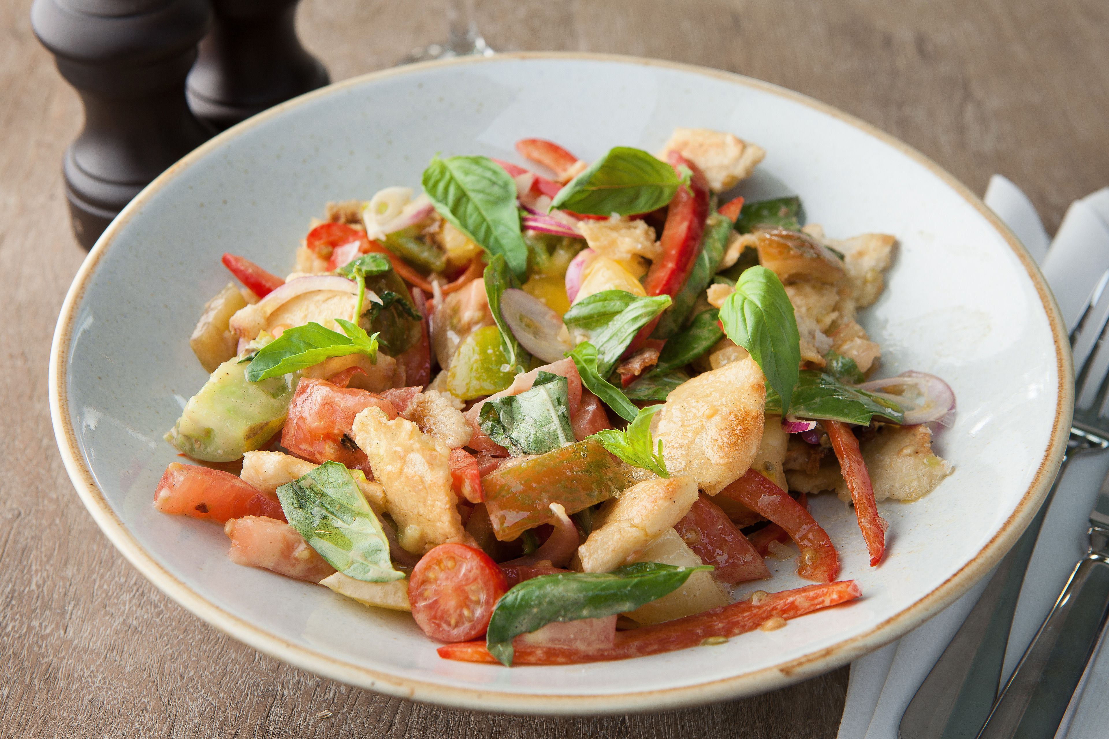 A bowl of salad with various vegetables and herbs.