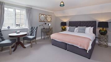Une chambre à coucher avec un grand lit, deux chaises, une petite table et un bureau.