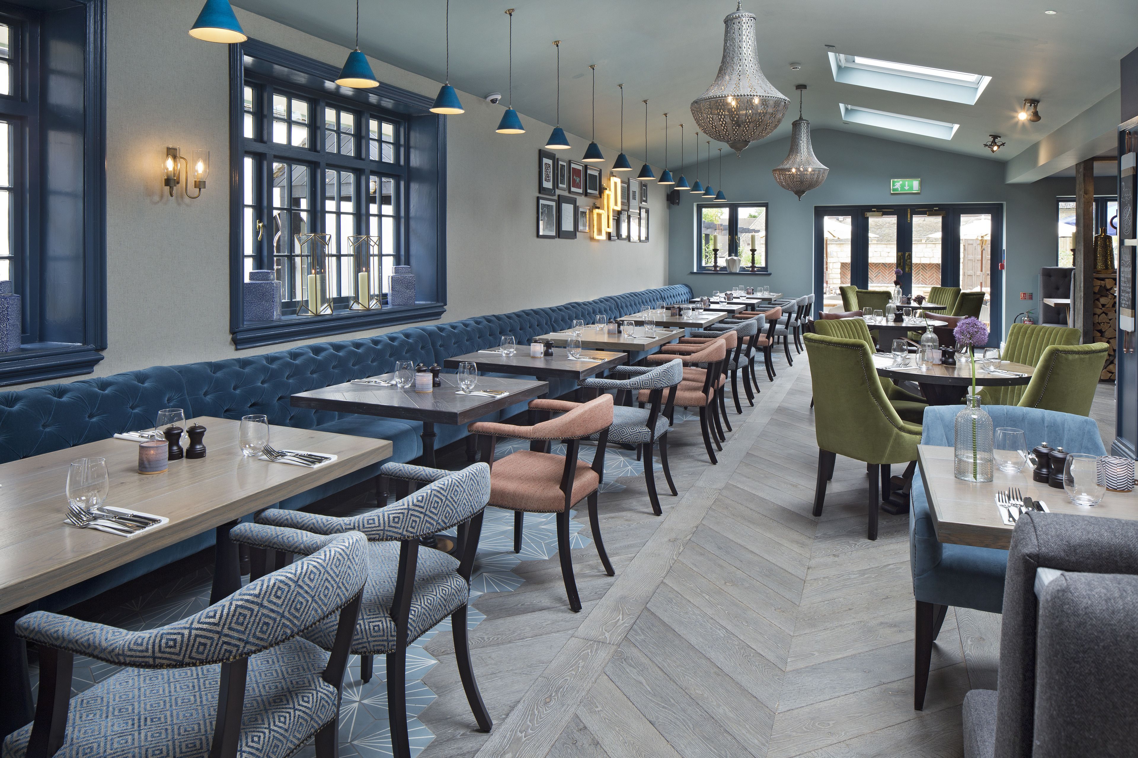 Ein Restaurant mit einer langen Theke, blauen gepolsterten Sitzecken und grünen Stühlen.