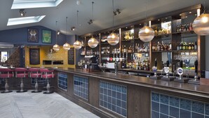 Eine Bar mit Theke, Hockstühlen und einer Auswahl an Flaschen und Gläsern.
