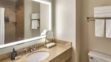 A bathroom with a granite countertop, a sink, a mirror, a towel rack, and a toilet.