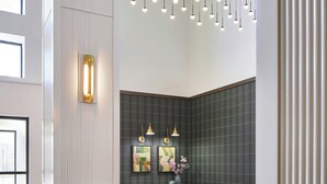 A modern dining area with a herringbone wood floor, a wooden table with chairs, pendant lighting, and a dark green accent wall with framed artwork. - Sheraton Birmingham Hotel (Birmingham)