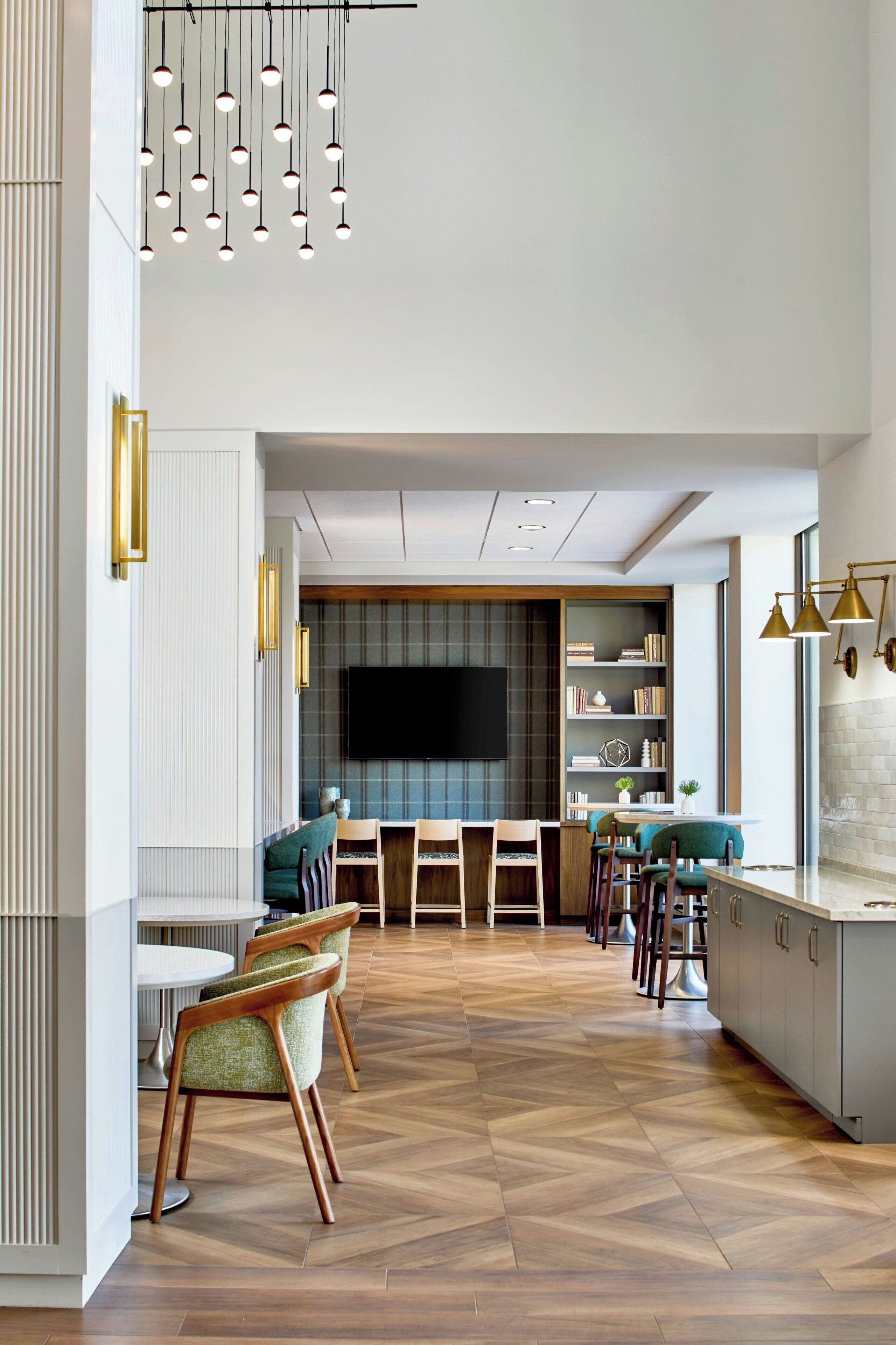 A modern kitchen with a herringbone wood floor, a central island with bar stools, and pendant lighting.