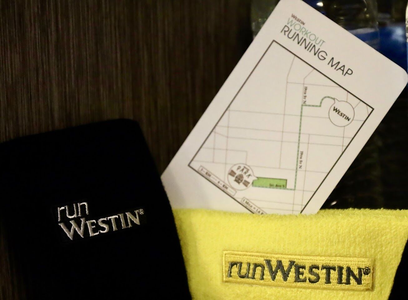 A black box with 'run WESTIN' embroidered on it, a yellow towel with 'run WESTIN' embroidered, and a 'Westin Workout Running Map' card.