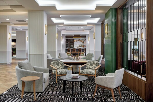 A modern hotel lobby with a round table surrounded by four armchairs, a patterned rug, and a green accent wall. - Sheraton Birmingham Hotel (Birmingham)