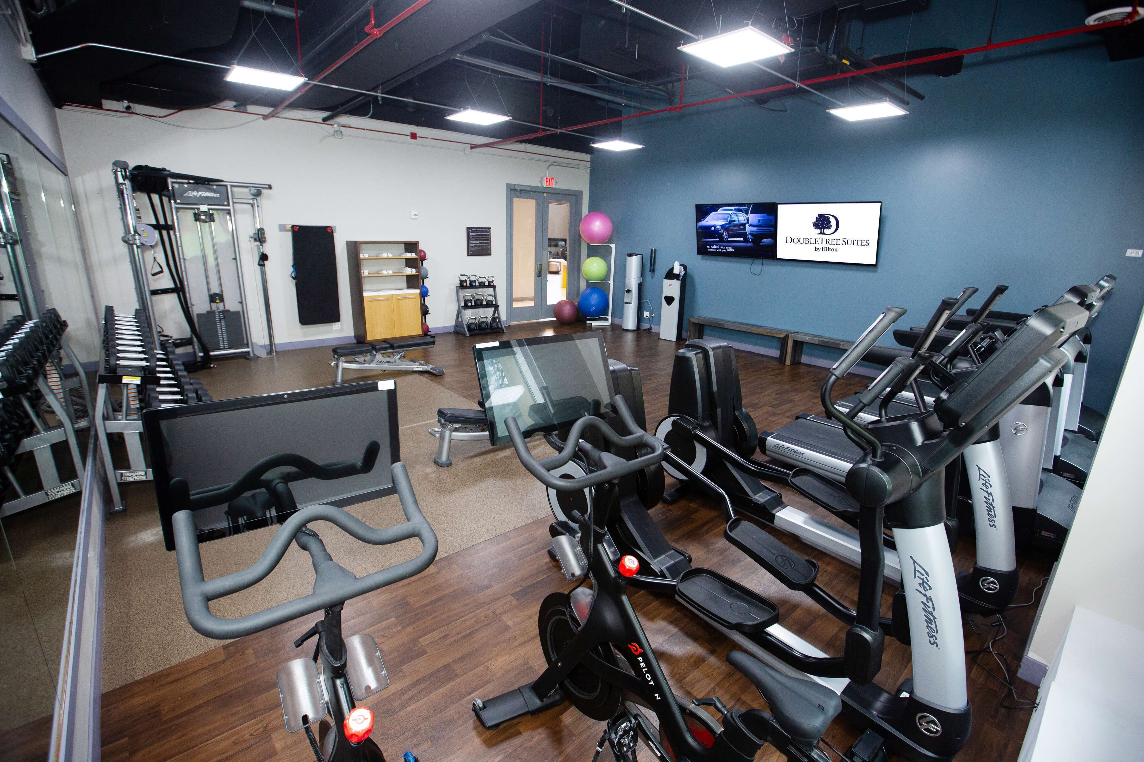 Une salle de sport équipée de tapis de course, de vélos d’appartement et d’appareils de musculation.