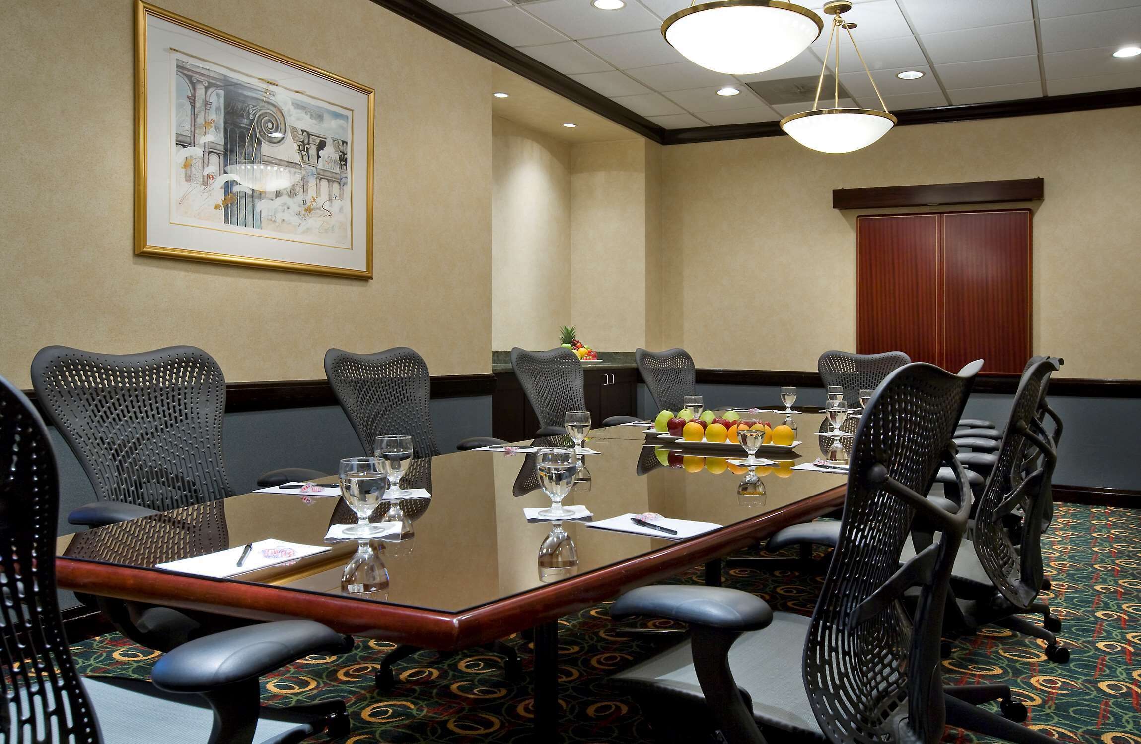 A conference room with a long table, chairs, and a fruit basket.
