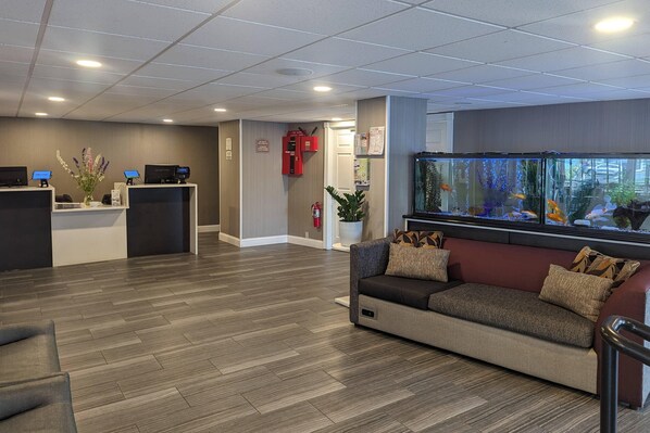 A reception area with a reception desk, a sofa, a fish tank, and a fire extinguisher.