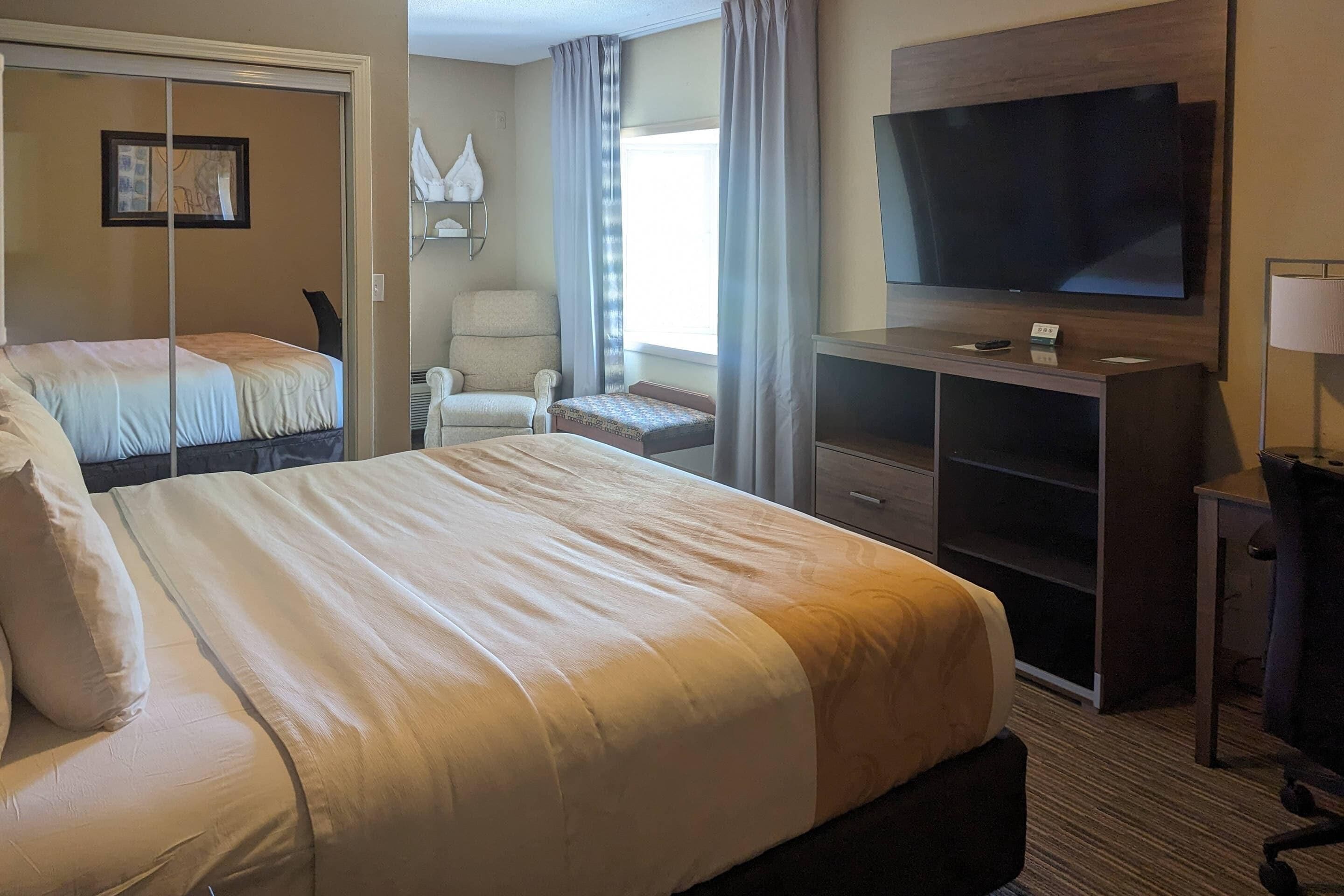 A hotel room with a large bed, a TV, a desk, and a chair.
