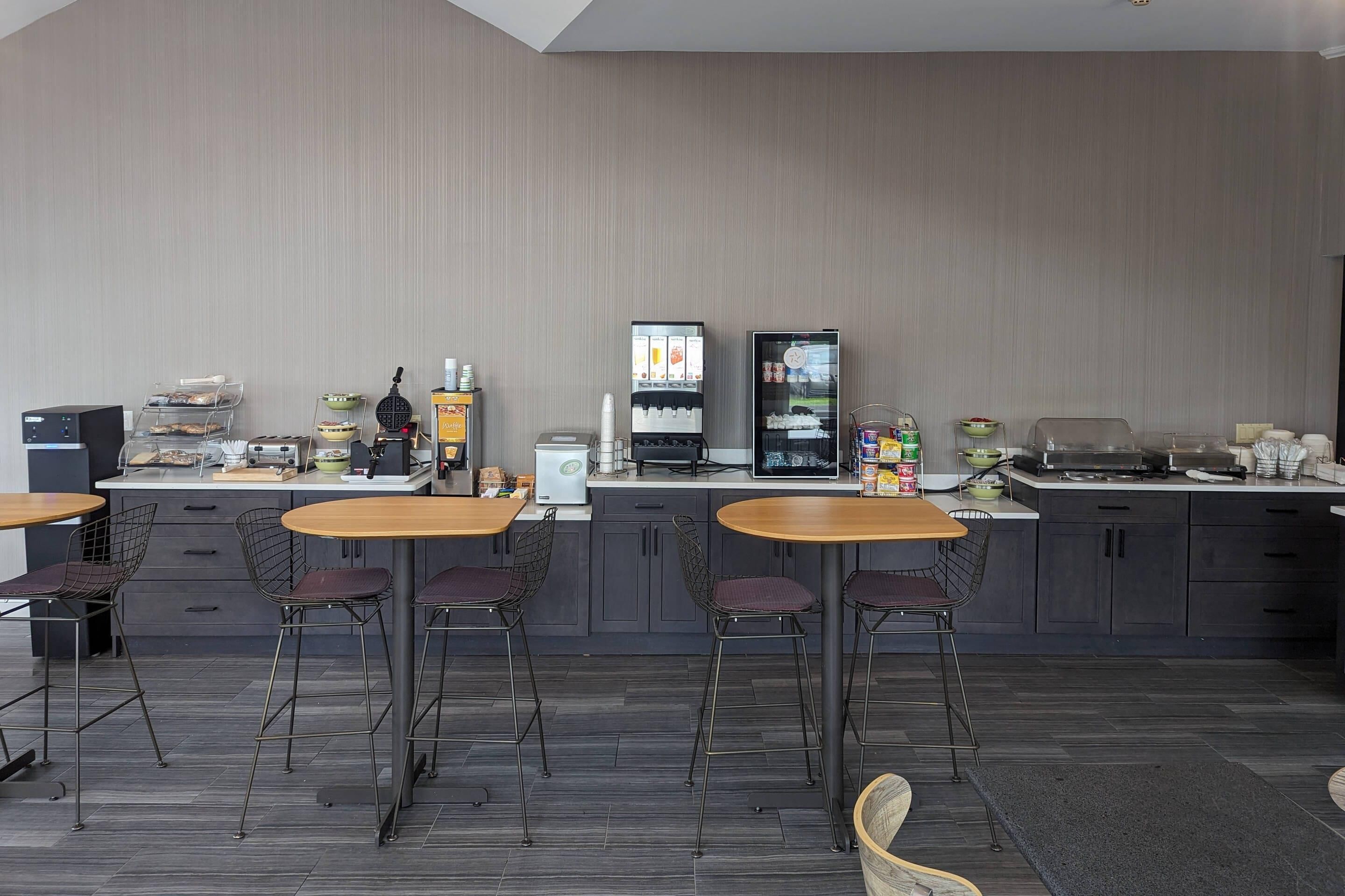 Une cuisine moderne équipée de tabourets de bar, d’une machine à café et d’un réfrigérateur.