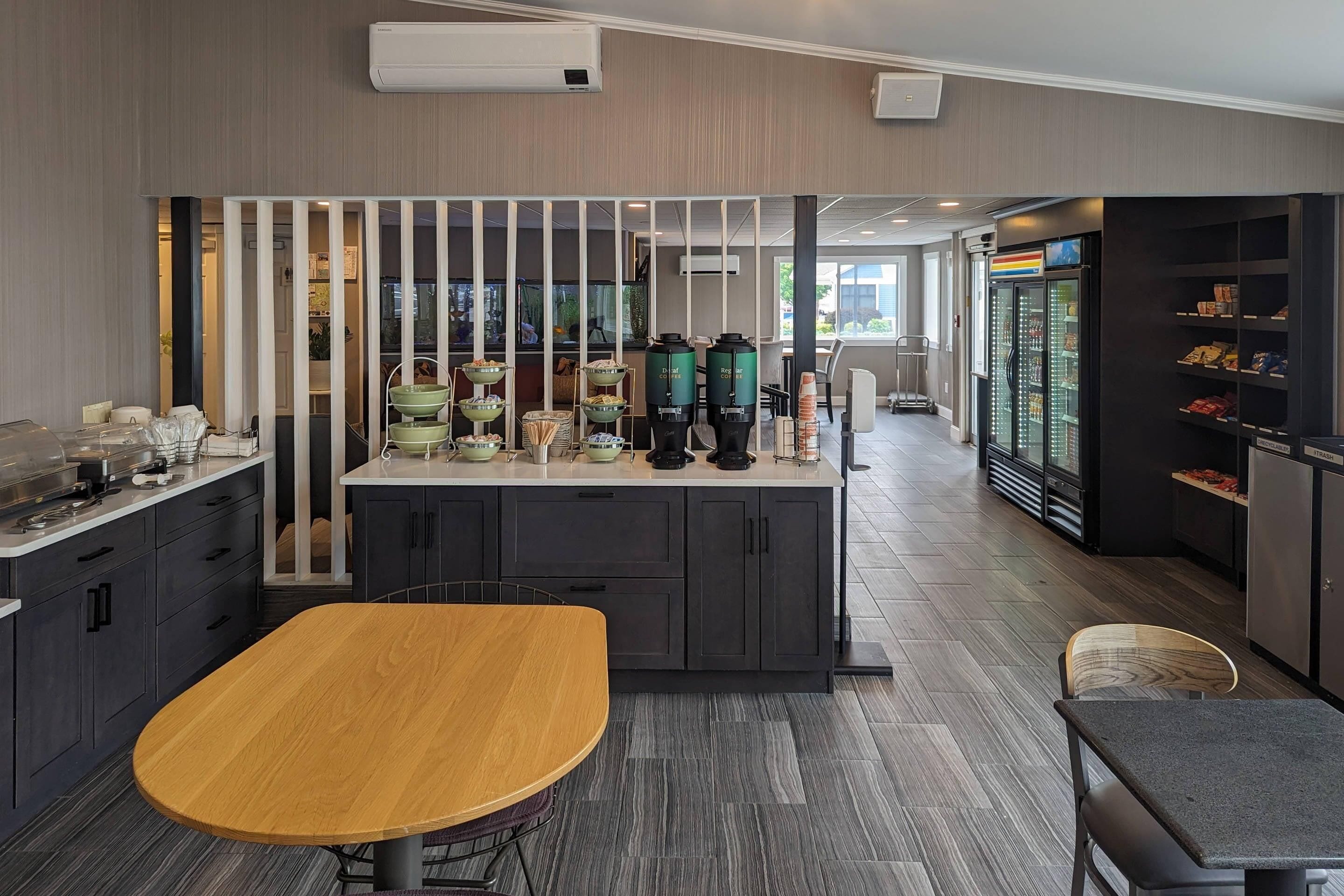 A modern kitchen with a central island, a refrigerator, and a coffee station.