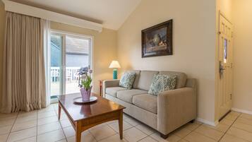 A living room with a sofa, a wooden coffee table, a lamp, and a painting on the wall.