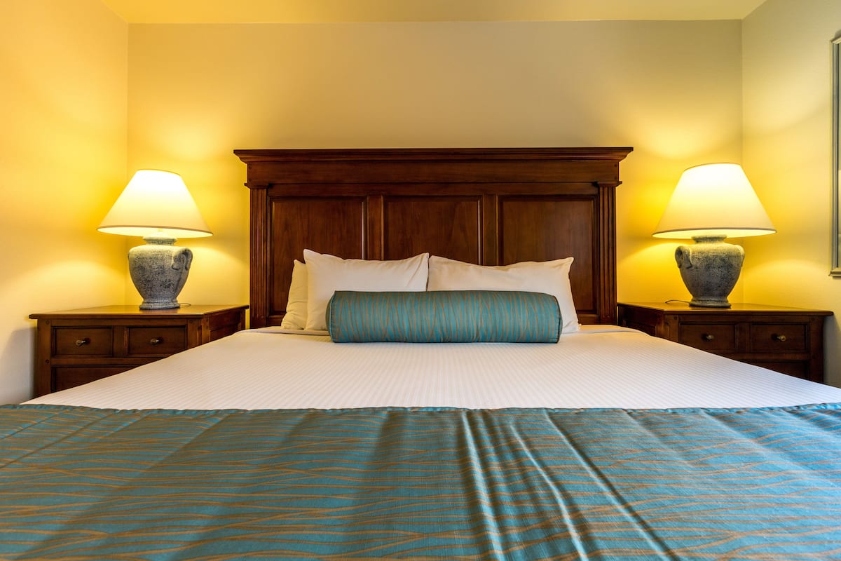 A neatly made bed with a blue patterned bedspread and two lamps on wooden nightstands.