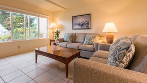 A living room with a sofa, a coffee table, two lamps, and a painting on the wall. - Channel Island Shores (Oxnard)