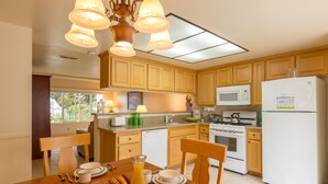 A kitchen with wooden cabinets, a microwave, a stove, and a refrigerator. - Channel Island Shores (Oxnard)
