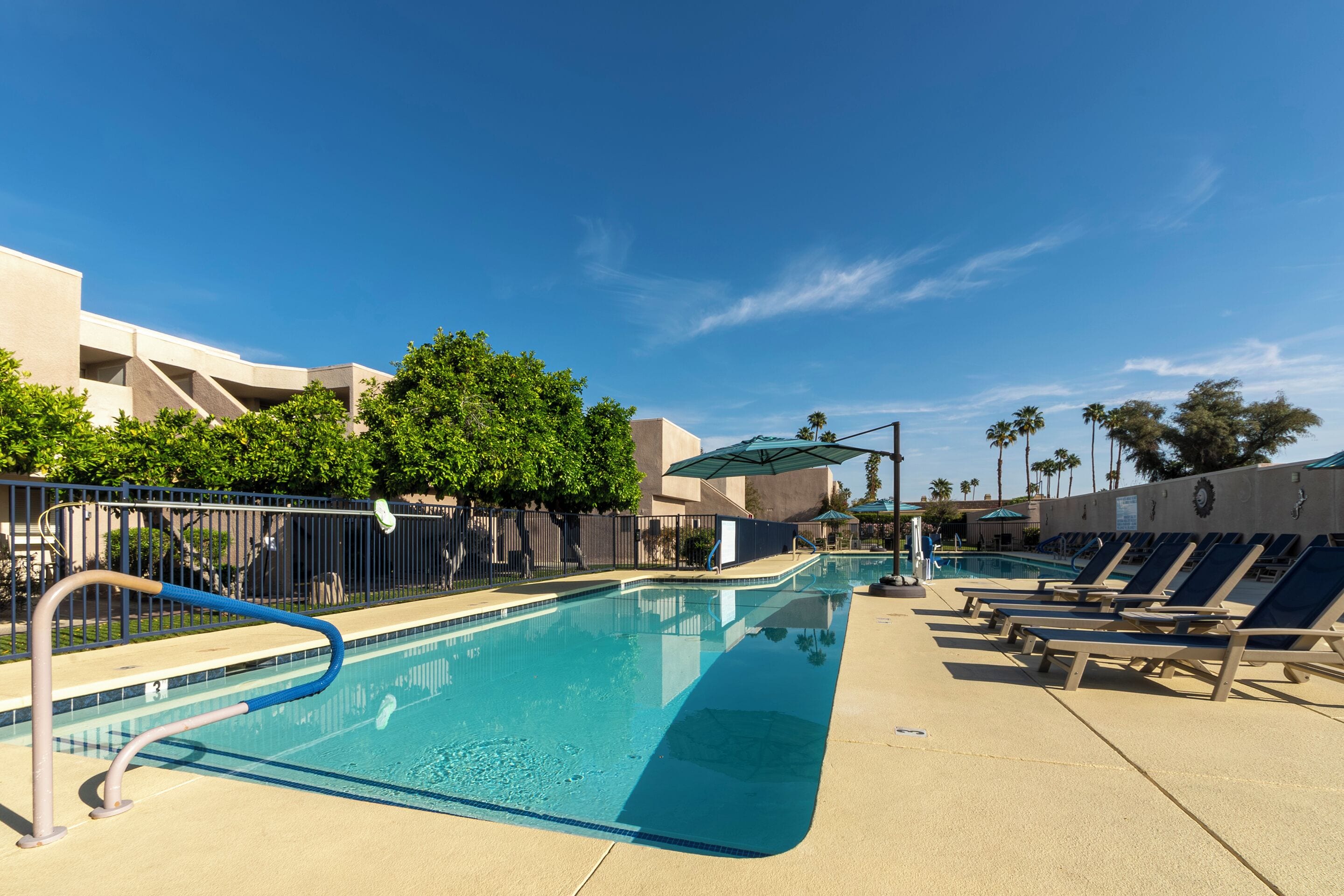 A swimming pool with lounge chairs and a fence.