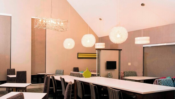 A conference room with a long table, chairs, and hanging spherical light fixtures.