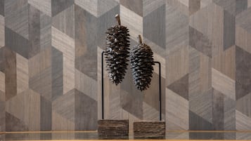 Two pine cones on a metal stand against a geometric patterned wall.