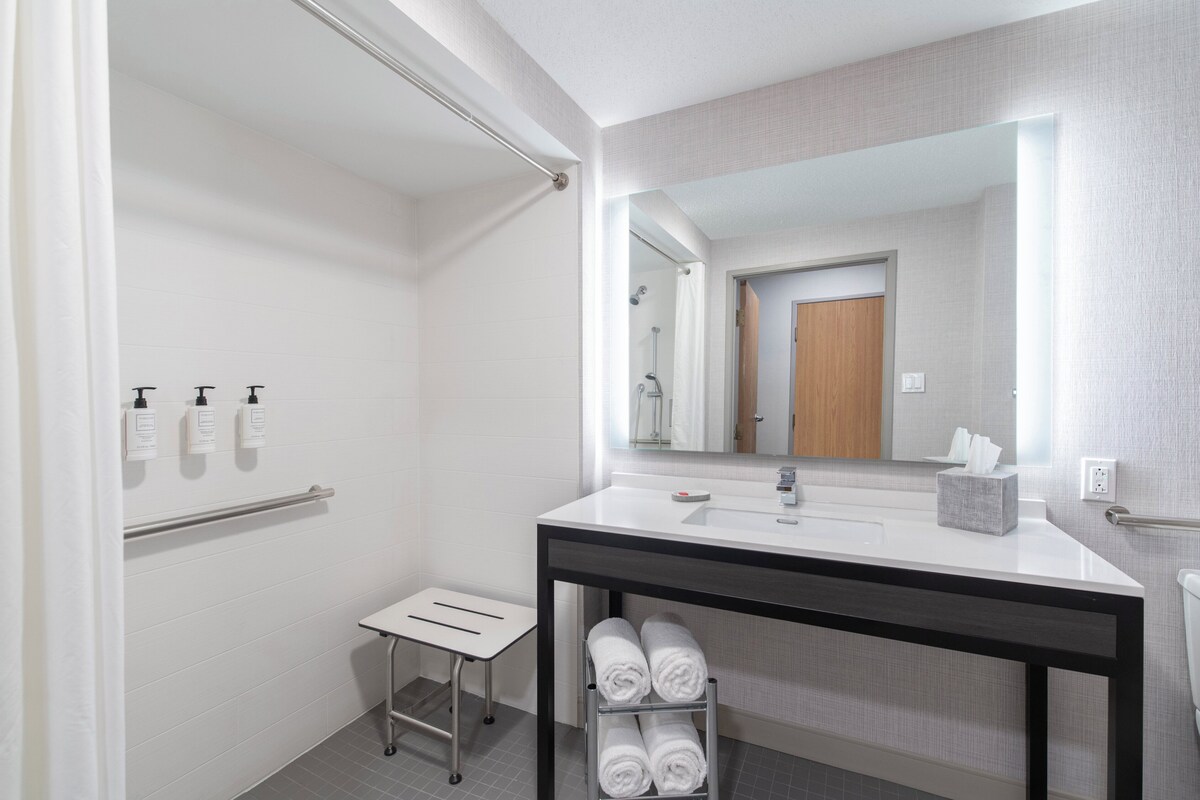 Une salle de bain moderne avec un lavabo blanc, un miroir et un porte-serviettes.