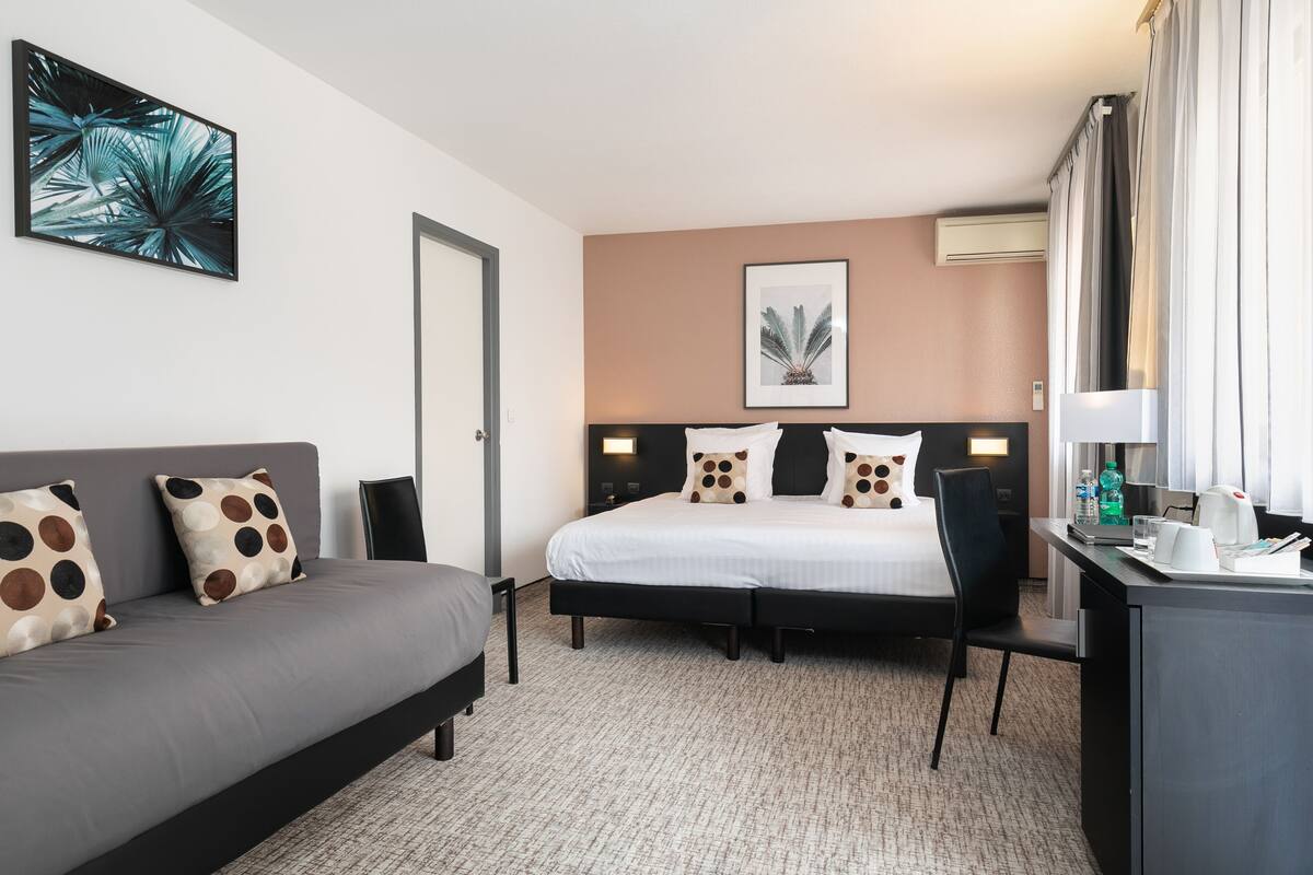 Ein Hotelzimmer mit Bett, Sofa, Schreibtisch und Stuhl.