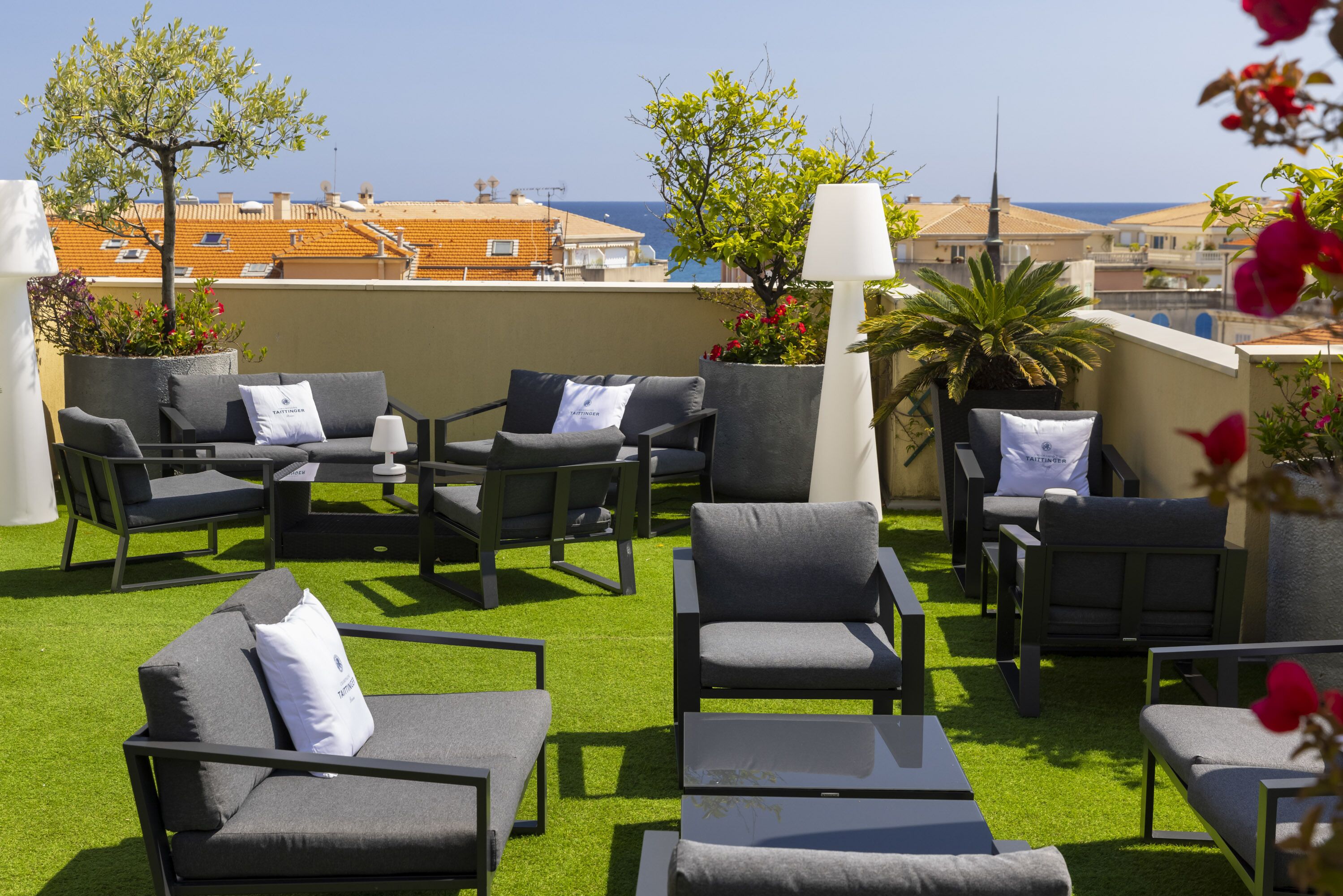 Une terrasse sur le toit avec des sièges extérieurs, un palmier et une vue sur la mer.