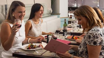 Un grupo de personas cenando en un restaurante, con una mesa preparada para la comida, un menú y copas de vino.