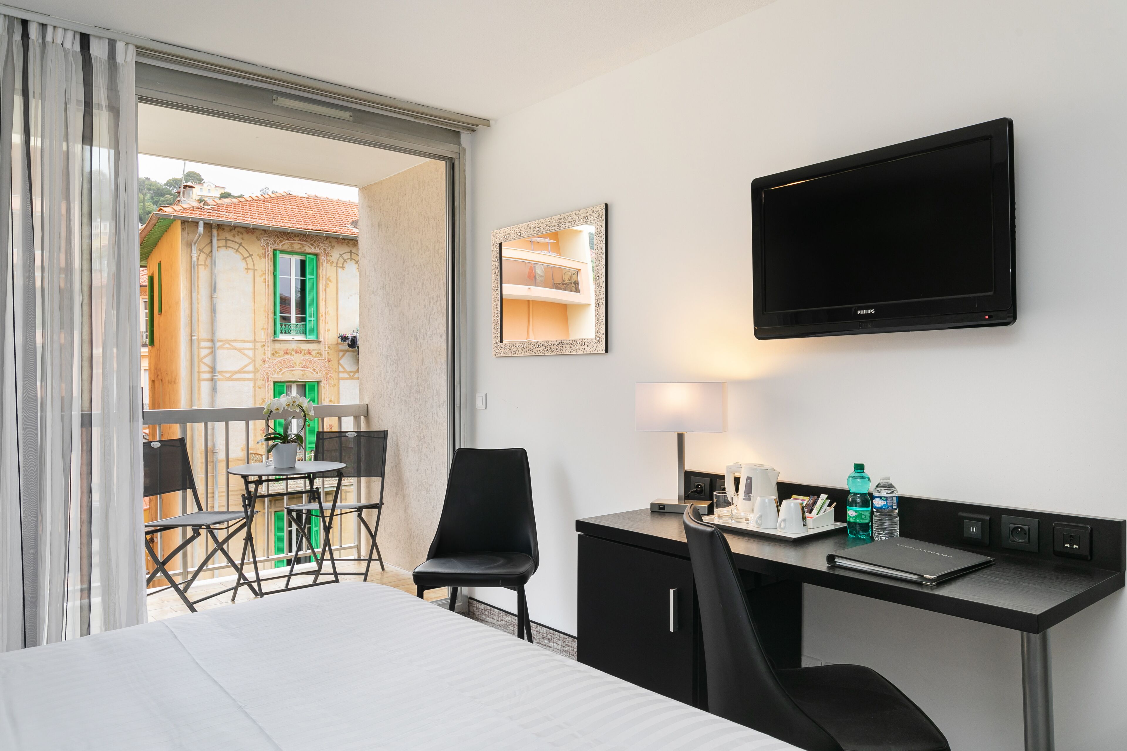 A hotel room with a bed, desk, chair, and a TV mounted on the wall.