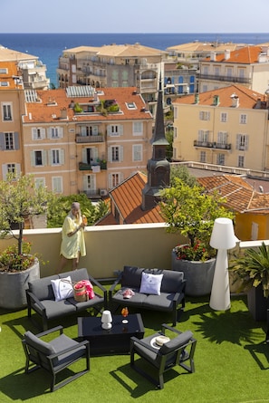 A rooftop terrace with outdoor furniture, potted plants, and a view of the cityscape and sea. - Best Western Hotel Mediterranee Menton (Menton)