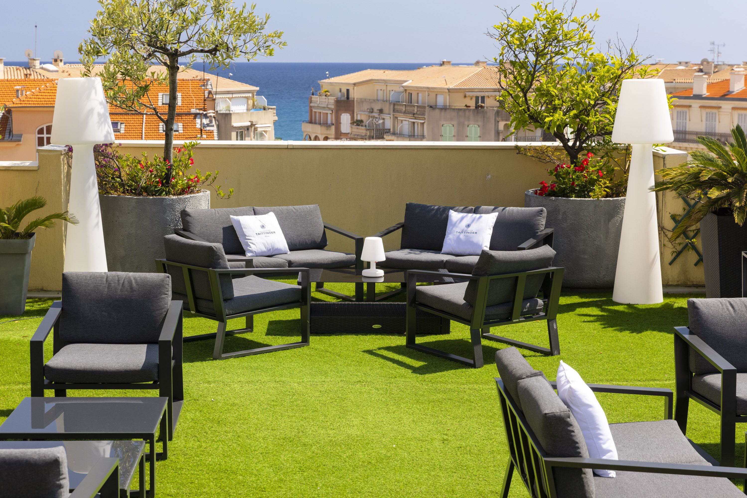 Terraza en la azotea con mobiliario exterior, una mesa y plantas en macetas.