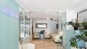 A reception area with a glass wall, a neon sign, seating, and potted plants. - Best Western Hotel Mediterranee Menton (Menton)