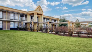 A hotel with a central atrium, multiple balconies, and a well-maintained lawn.