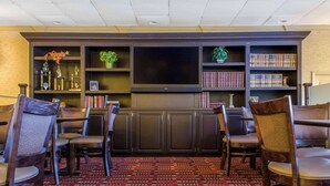 A bar area with a flat-screen TV, bookshelves, and chairs.
