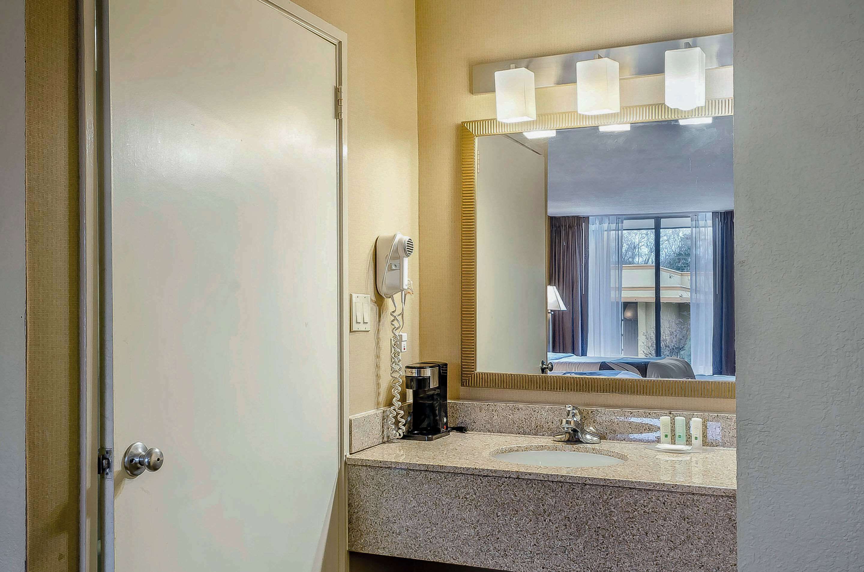 A bathroom with a sink, mirror, and hair dryer.