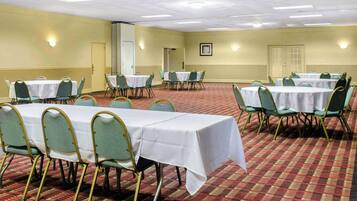 A conference room with multiple tables and chairs, carpeted floor, and walls with light fixtures.