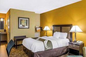 A hotel room with a bed, bedside tables, a desk, and a chair. - Quality Inn University Area (Troy)