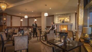 A restaurant with multiple tables, chairs, and a fireplace.