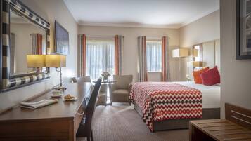 A hotel room with a bed, a desk, a chair, a lamp, and a mirror.