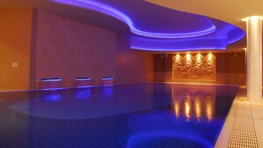 A modern indoor swimming pool with blue LED lighting, a textured wall, and a decorative wall panel. - The Royal Marine Hotel (Dublin)