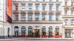 Un edificio histórico con fachada clásica, una entrada central con un letrero y una hilera de ventanas.